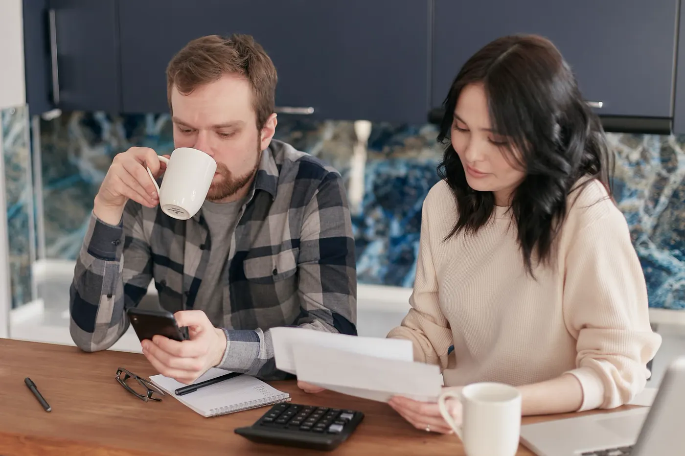 A couple reviewing bills with a calculator and phone.