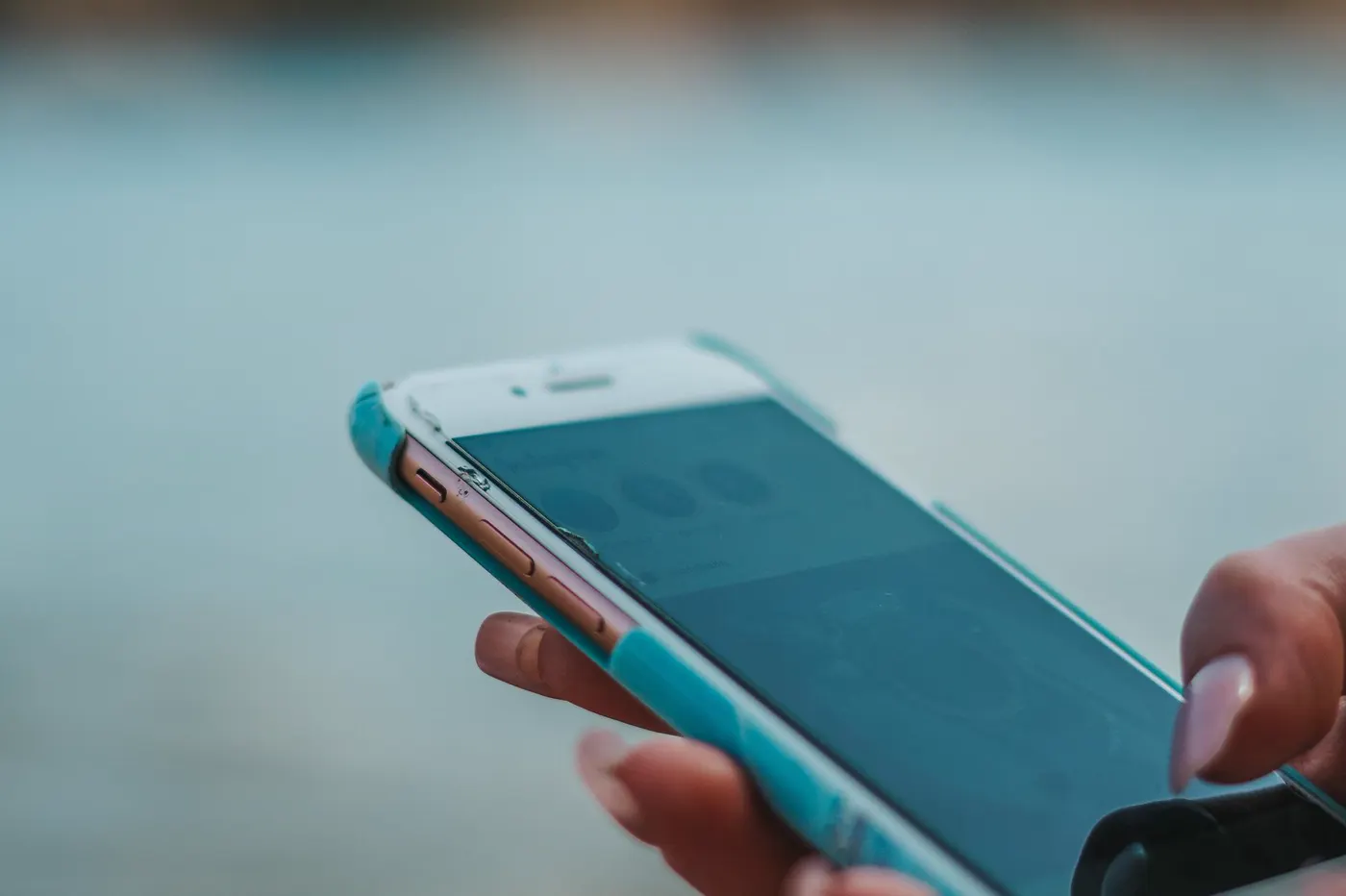 A person using a smartphone beside reflective water.