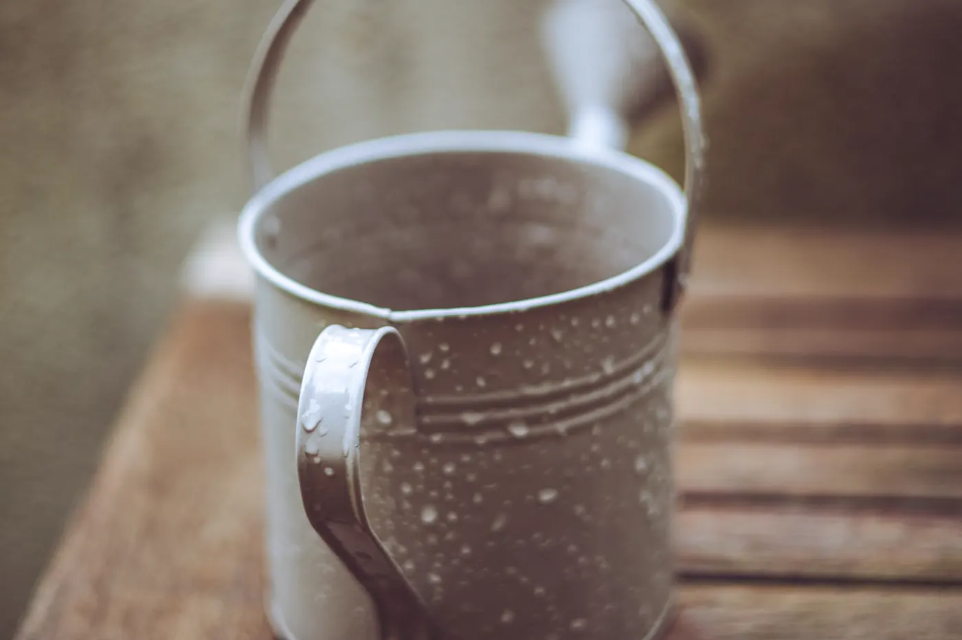 A wet metal bucket outdoors after rain.