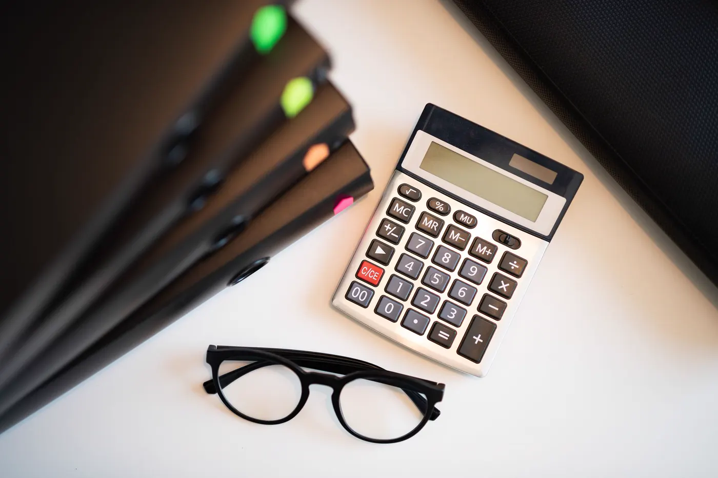 Calculator, folders, glasses, and organized documents on a desk.