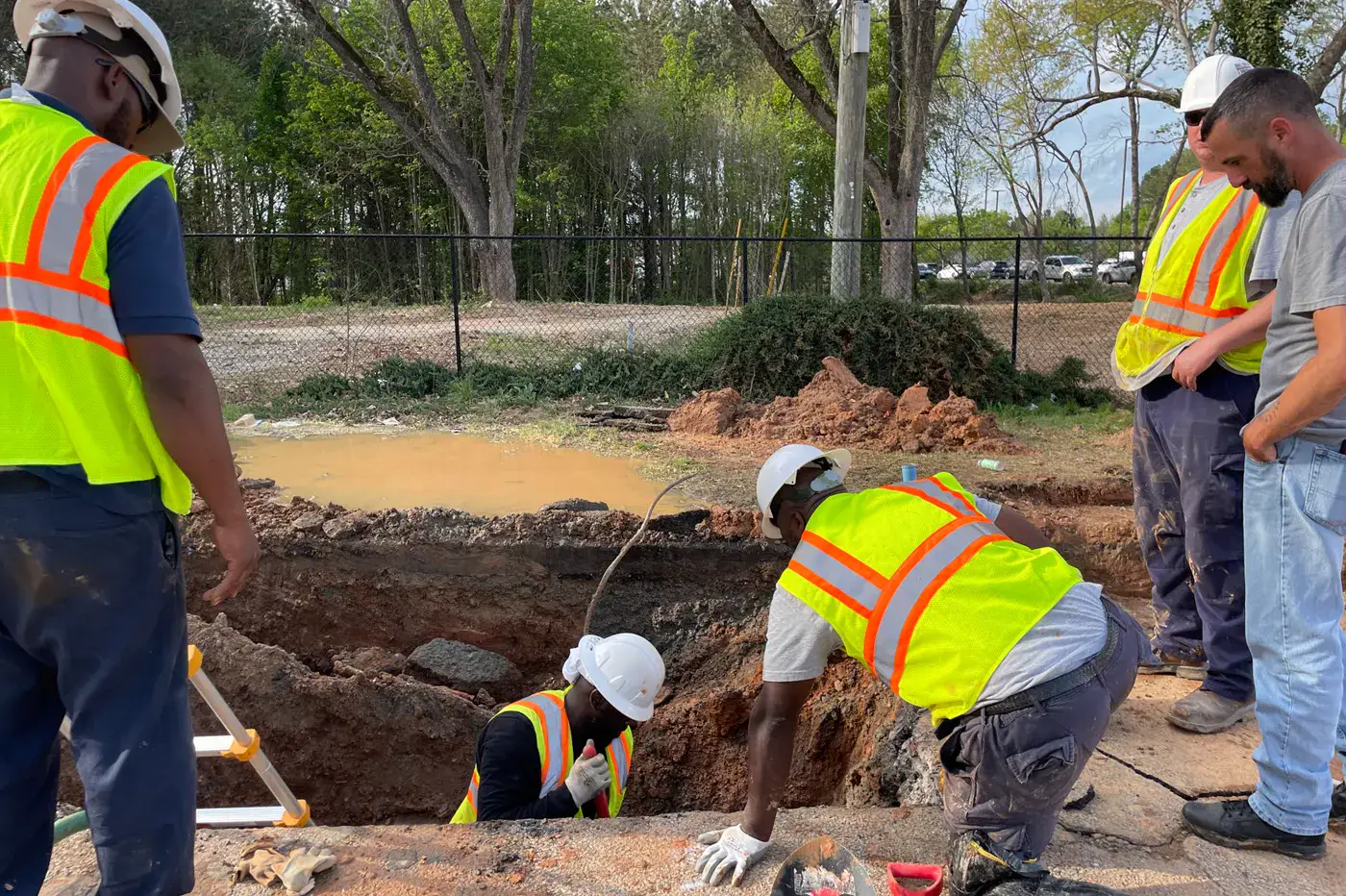 Utility workers inspecting an excavated underground service area.