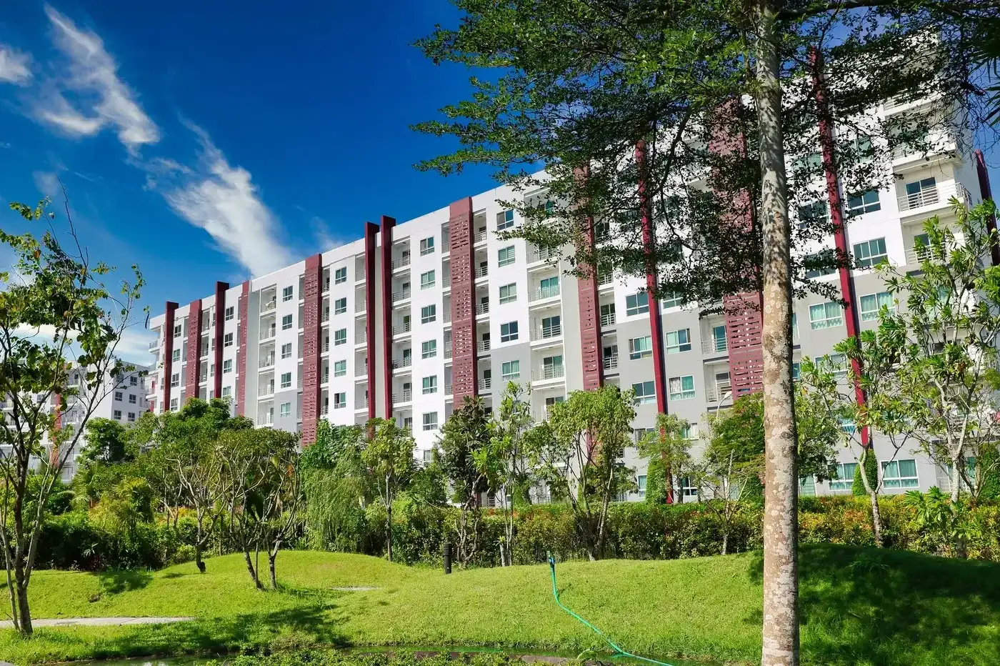 A mid-rise apartment building beside a green park.