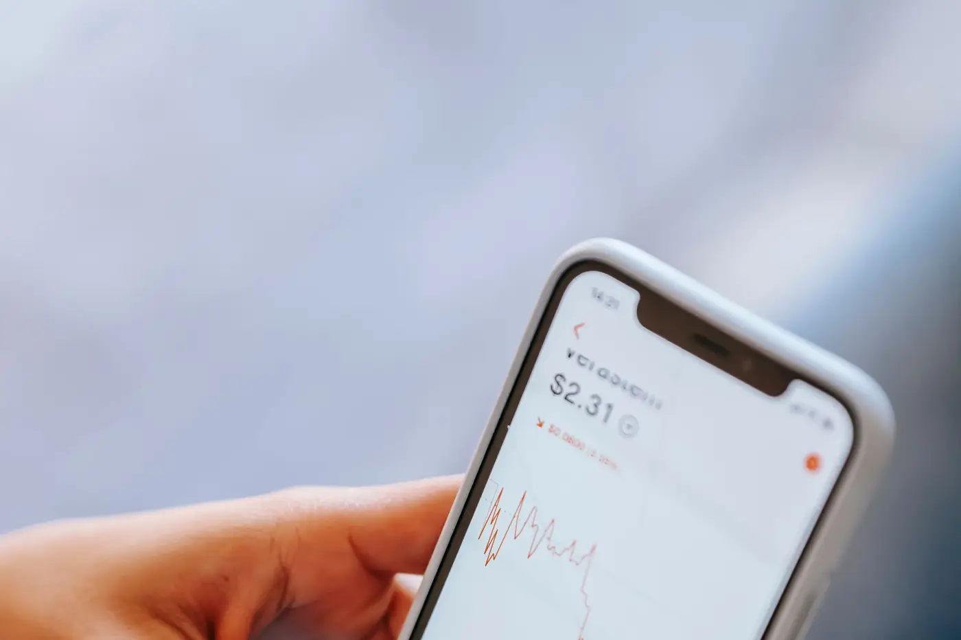 A hand holding a smartphone showing a finance app.
