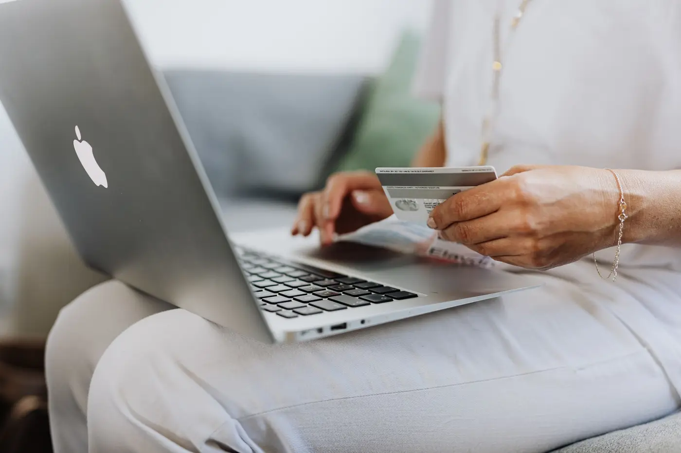 A person holding a credit card while using a laptop.