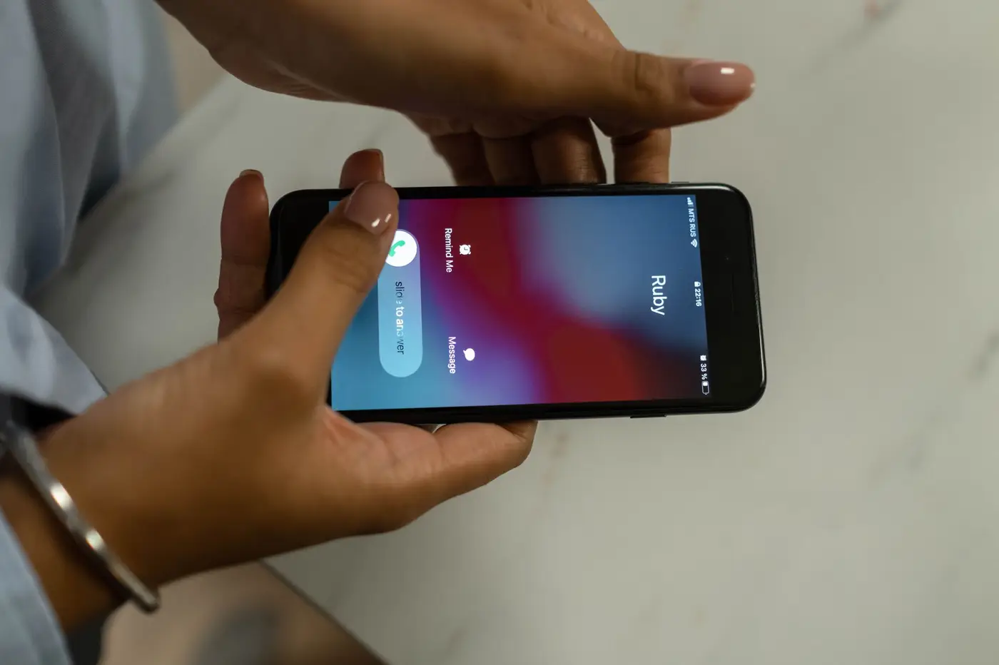 Hands holding a smartphone showing an incoming call.